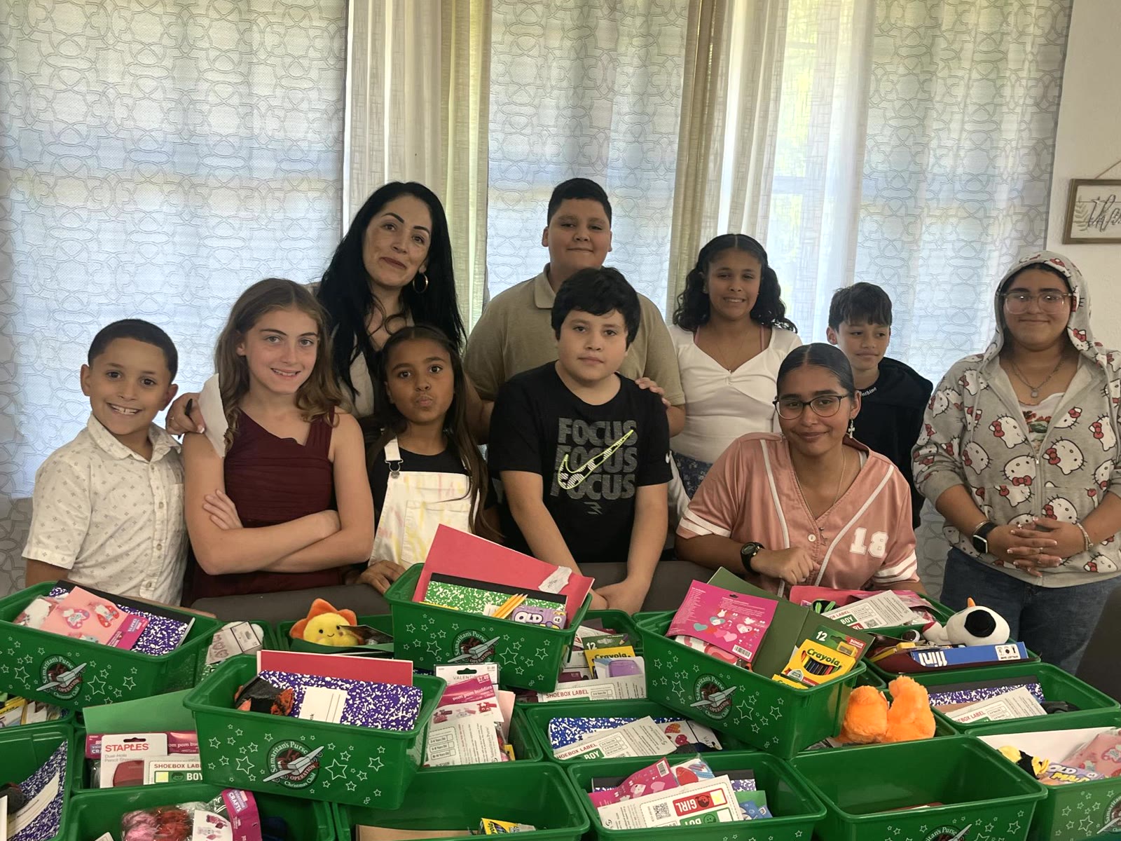 La pastora Teresita y nueve niños de la iglesia detrás de las cajas de Operation Christmas Child que acaban de llenar con juguetes, útiles y ropa